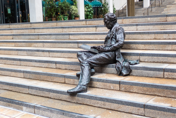 set of outdoor steps with a statue of a reclining man writing in a large book