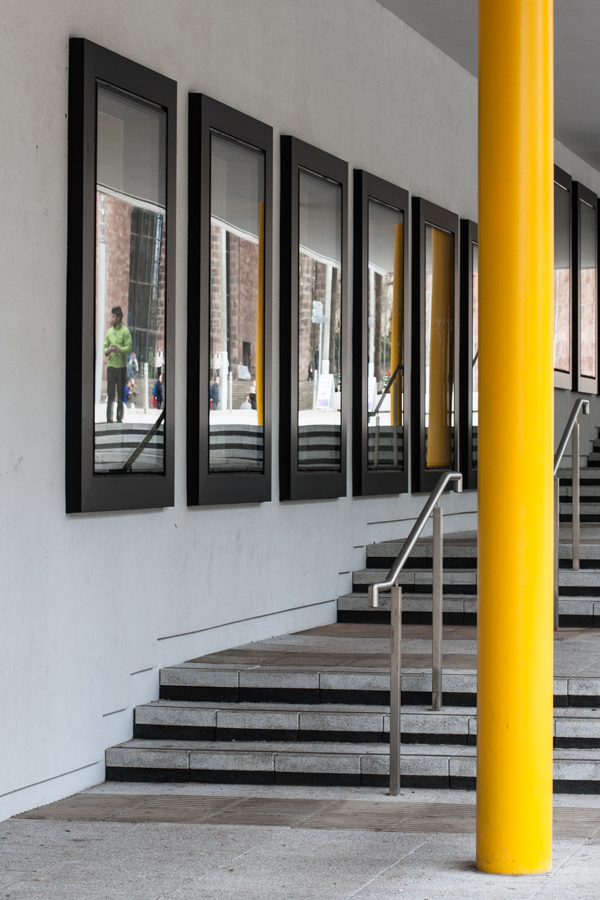 colour photograph steps reflected in five wall mounted frames with a yellow pole at the front