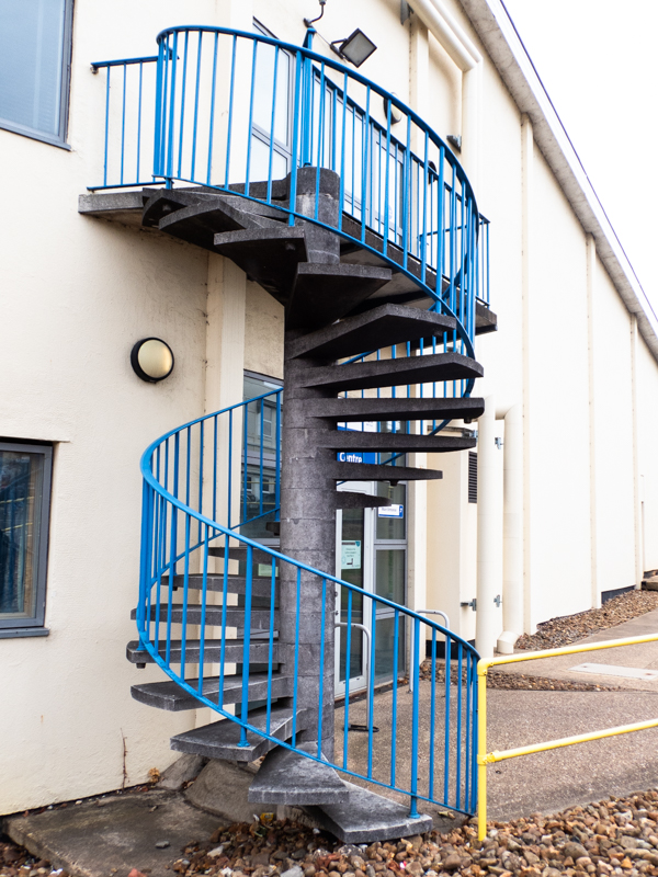 colour image of a blue spiral staircase up the outside of a white building